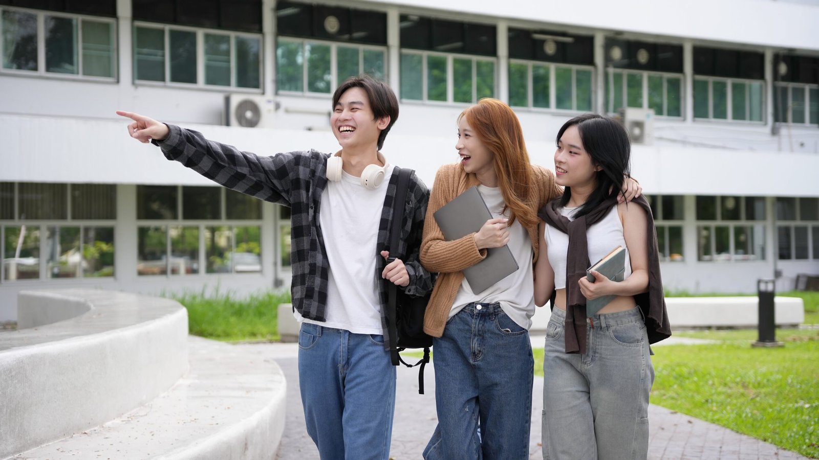 Three,Asian,Students,Stroll,Through,The,University,Campus,,Engaged,In